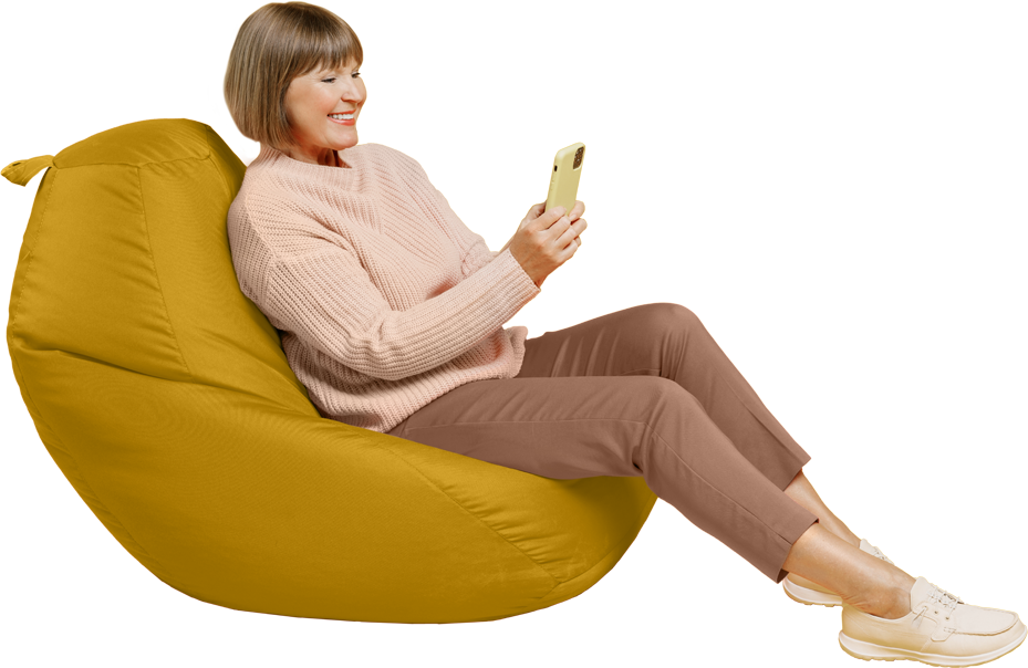 Woman sitting on a bean bag chair while participating in a telehealth visit on her mobile phone